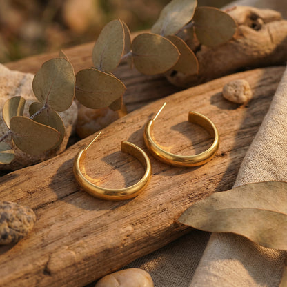 The beautiful 14K Gold Plated Golden Hour Earring Set by Astral Signature™ elegantly placed on a wooden surface surrounded by natural elements. This limited edition design represents the essence of Astral Design, making it a perfect gift for her.