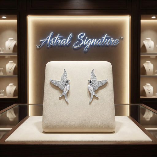The Celestial Hummingbird Earrings displayed beautifully on a presentation set in an Astral Signature jewelry showcase. These white gold plated eco-brass earrings, adorned with zirconia, are a perfect gift for her, elegantly combining style and comfort with S925 sterling silver posts.