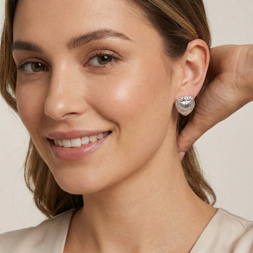 A model wearing the beautiful Shell Goddess Earrings featuring a sculptural shell design, made by Astral Signature™. Ideal as a gift for her, these earrings combine sterling silver (S925) with white gold plated eco-brass and zirconia for a dazzling look.