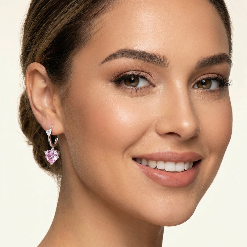 Model showcasing Pink Heart Drop Hoops by Astral Signature, sparkling pink zirconia accents on Eco-Brass earrings enhance her look. An ideal gift for her, these White Gold Plated Eco-Brass earrings capture timeless beauty.