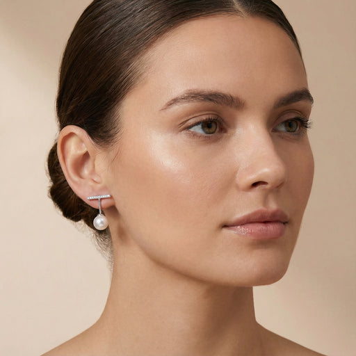 A side profile of a woman wearing the Pearl Drop T-Bar Earrings - Freshwater Pearl - Rhodium-Plated 925 Sterling Silver by Astral Signature. The earrings reflect a blend of modernity and elegance, perfect for any occasion. An ideal everyday wear option or a thoughtful gift for her, these earrings are featured in the Limited Edition collection by Astral Design.