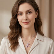A model showcases the Pink Cross Heart Necklace from Astral Signature, highlighting its elegant design with a pink teddy bear charm, crafted from Eco-Brass and zirconia, ideal for stylish layering.