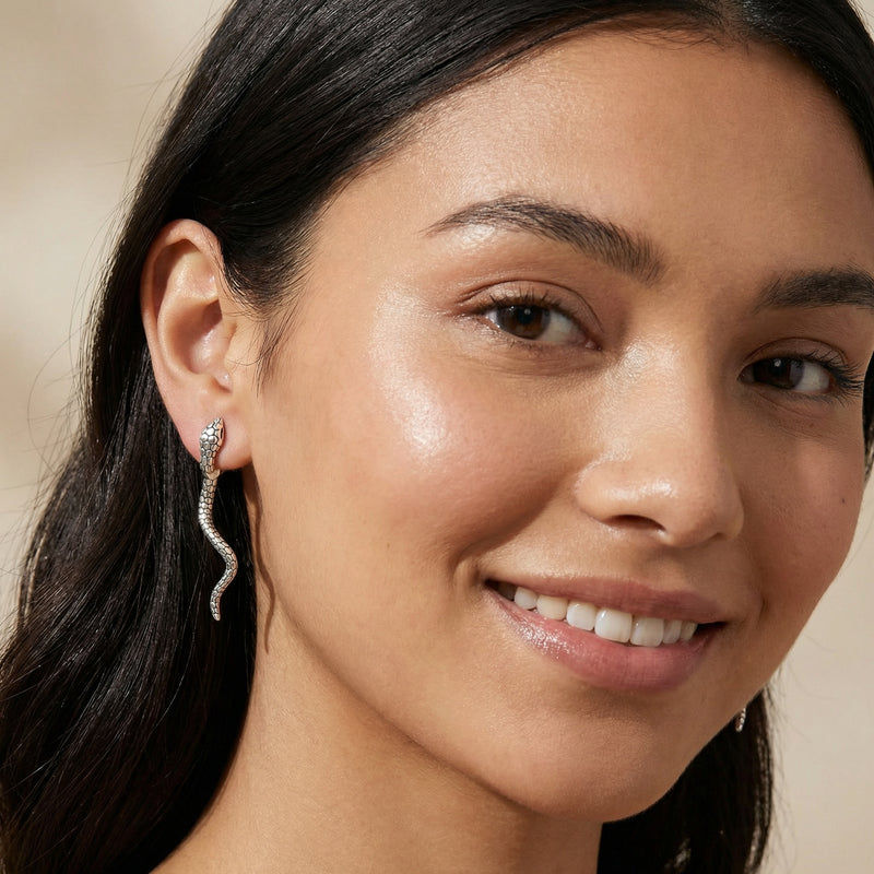 Close-up of the Serpent Spell Earrings worn by a model, showcasing the intricate details in white gold plated Eco-Brass. An elegant gift for her, these earrings are designed with S925 Sterling Silver posts for a comfortable fit.