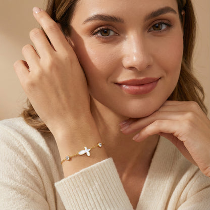 A woman elegantly showcasing the 18K Plated Gold Sacred Cross Bracelet by Astral Signature, highlighting its exquisite design, suitable for everyday wear. An ideal gift for her, this limited edition piece captures the essence of Astral Design and individual style.