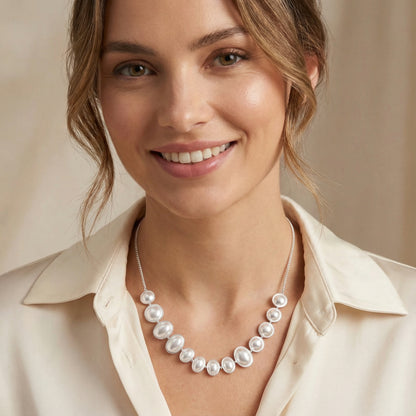Happy woman adorned with the Lunar Pearl Arc Necklace - Sterling Silver by Astral Signature, radiating sophistication. An exquisite gift for her, this piece is crafted with Astral Design flair and is a limited edition item.