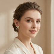A model wearing the Ribbon Dreams Bow Earrings by Astral Signature, highlighting the elegant 18K Gold Plated Eco-Brass construction. These stunning earrings feature zirconia and are ideal Eco-Brass Earrings for any occasion, making them a beautiful Gift for Her.