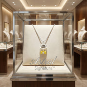 The Cosmic Dreamer Necklace displayed elegantly in a glass showcase, featuring a playful chrome egg pendant with a yellow bow by Astral Signature, showcasing its white gold plated Eco-Brass shine. Cosmic Dreamer Necklace, Eco-Brass Necklaces, Necklace, White Gold Plated Eco-Brass.