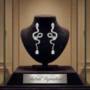 Serpentine Crystal Drops displayed in an elegant case by Astral Signature, showcasing exquisite drops and earrings made from Eco-Brass. These White Gold Plated Eco-Brass earrings are adorned with zirconia and Sterling Silver (S925) elements.