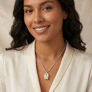 A woman wearing the Cosmic Dreamer Necklace from Astral Signature, which features a charming chrome egg pendant with kawaii details and a yellow bow, perfect for casual and chic outfits. Cosmic Dreamer Necklace, Eco-Brass Necklaces, Necklace, White Gold Plated Eco-Brass.