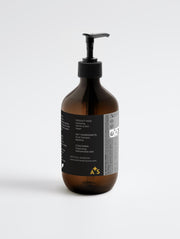 The back view of Astral Signature Hand & Body Wash, Ginger & Smoky Cardamom highlighting its natural certified formula, suitable for all skin types. This gentle body wash features hydrating betaine, is vegan, gluten-free, and allergen label free, crafted in an amber packaging that signifies organic ingredients for daily use.